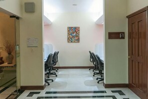 A conference room with two rows of chairs, a painting on the wall, and a door with a sign. - Holiday Inn CD. DEL CARMEN by IHG (Ciudad Del Carmen)