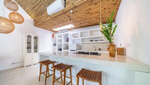 A modern kitchen with a central island, white cabinetry, and a bamboo ceiling. - The Oasis Villa (Kerobokan)