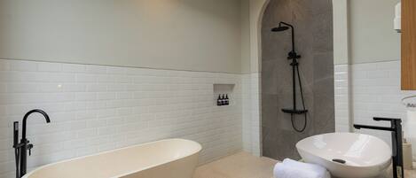 A modern bathroom with a freestanding bathtub, a built-in sink, and a shower.