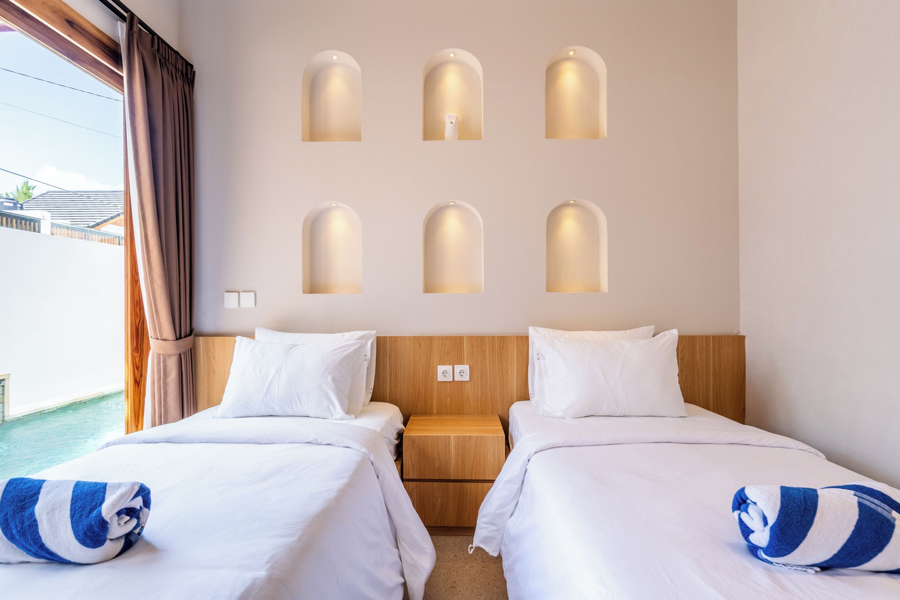 Ein Hotelzimmer mit zwei Betten, einem hölzernen Kopfteil und Blick auf das Meer.