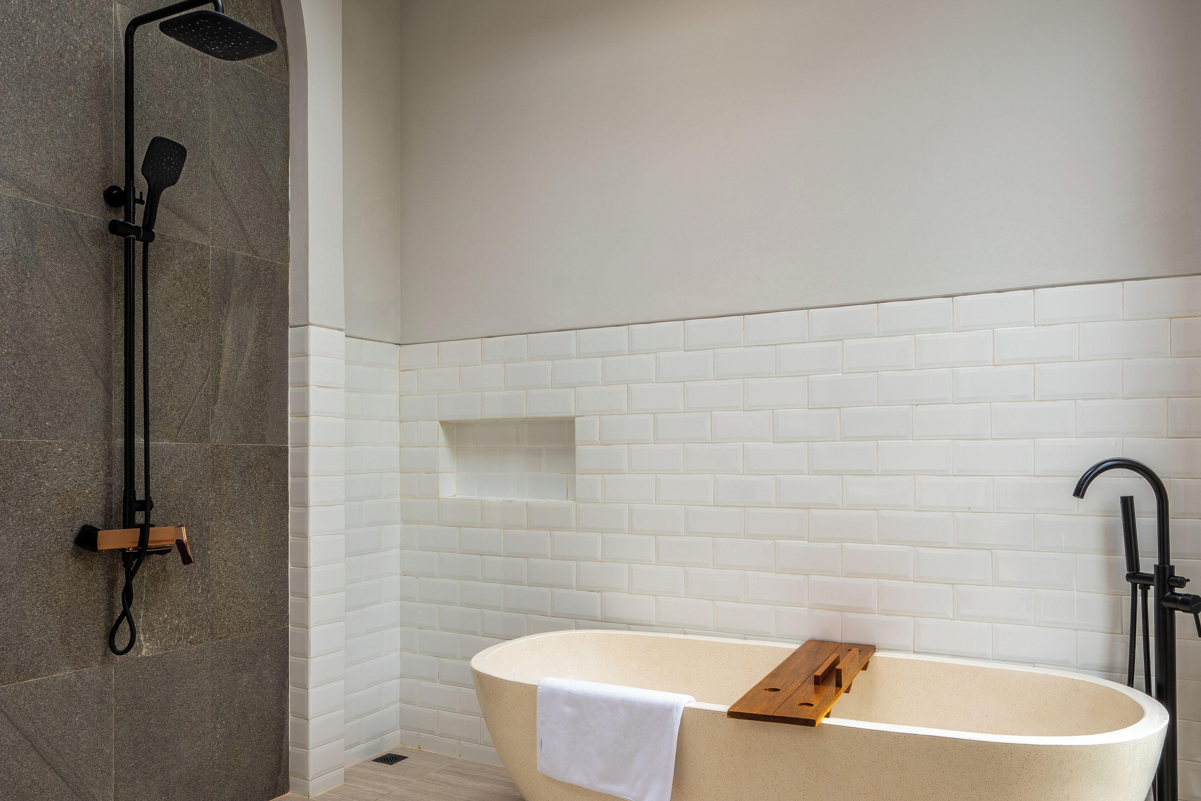 A modern bathroom with a freestanding bathtub, a showerhead, and a towel rack.