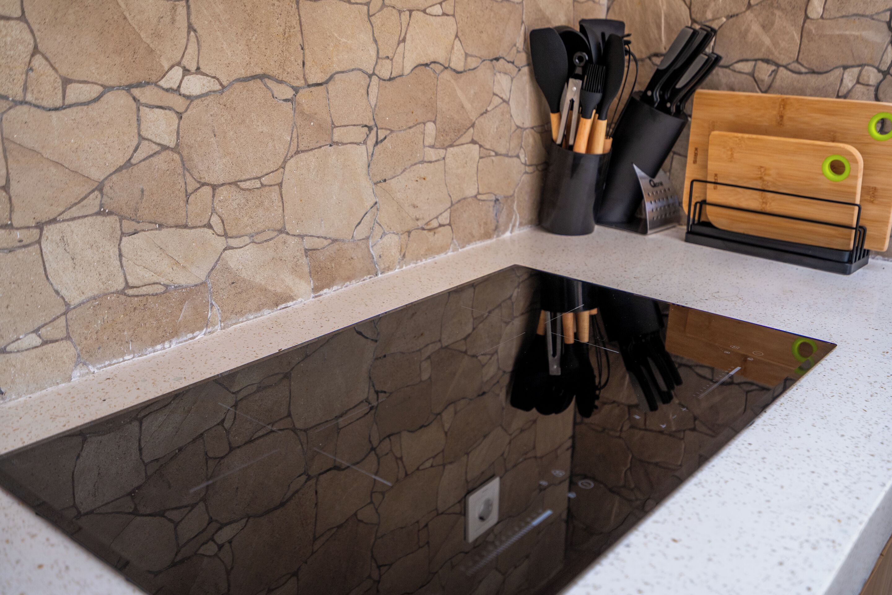 Una cocina con protector de piedra, encimera y bloque de cuchillos con utensilios.