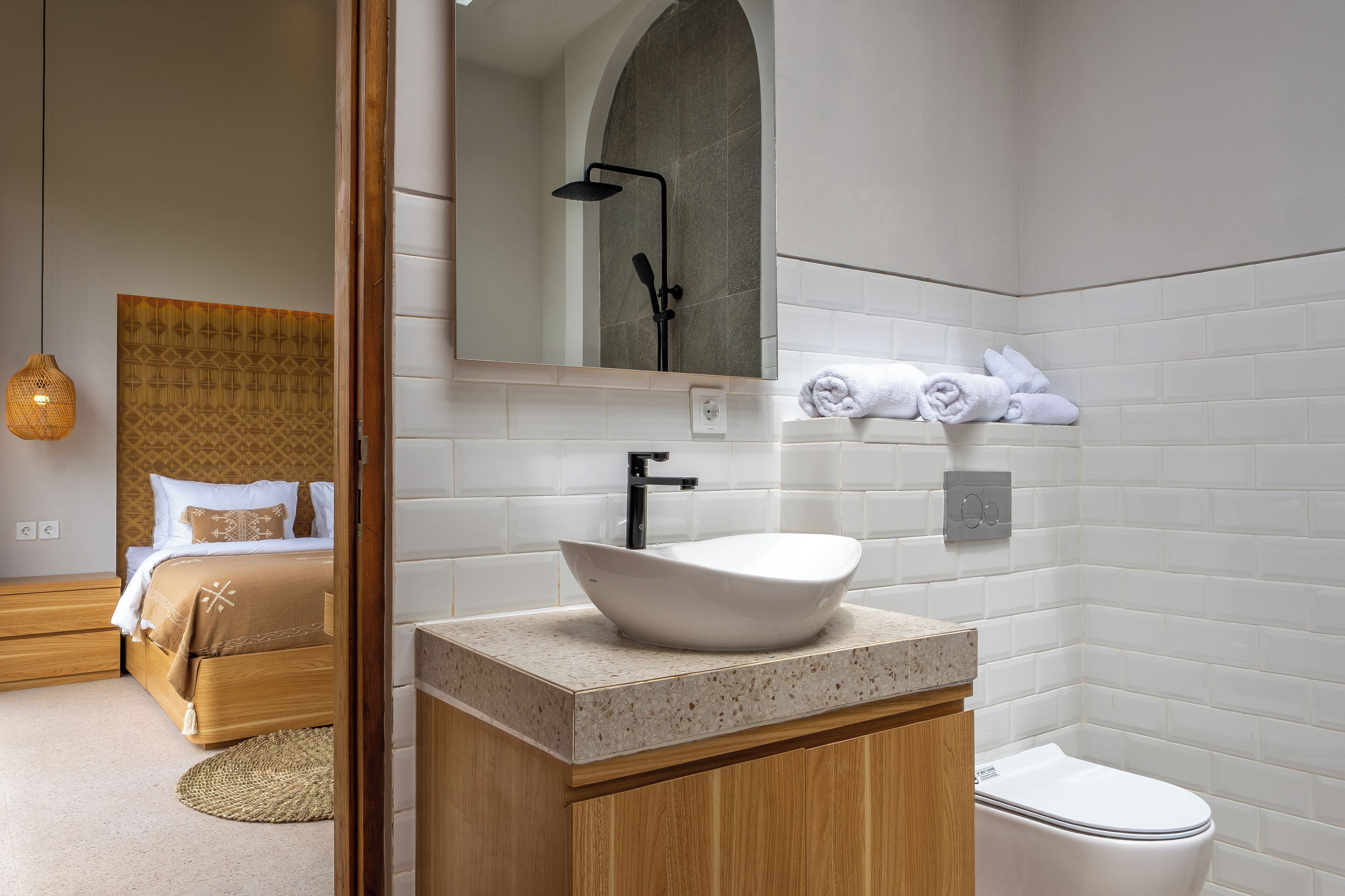 A modern bathroom with a freestanding sink, a toilet, and a shower area.