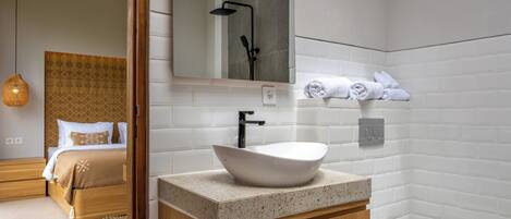 A modern bathroom with a freestanding sink, a toilet, and a shower area.