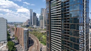 Ein Hochhaus mit moderner Glasfassade, umgeben von weiteren hohen Gebäuden und einem Gleis.