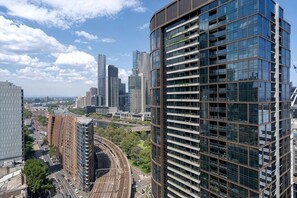 A high-rise building with a modern glass facade, surrounded by other tall buildings and a railway track. - 1B1B Condo with Bay &River Views (Docklands)