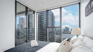Ein Hotelzimmer mit Bett, Stuhl, Fenster mit Stadtblick und Balkon.