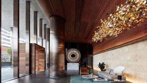 Eine moderne Lobby mit einem großen, runden Wandkunstwerk, einer Sitzecke mit einer Couch und einem Couchtisch, sowie einem großen Fenster mit Blick ins Freie.