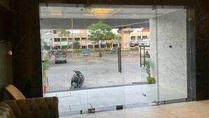 Um hall com porta de vidro que dá para o exterior, piso de mármore e área de estar com um sofá.