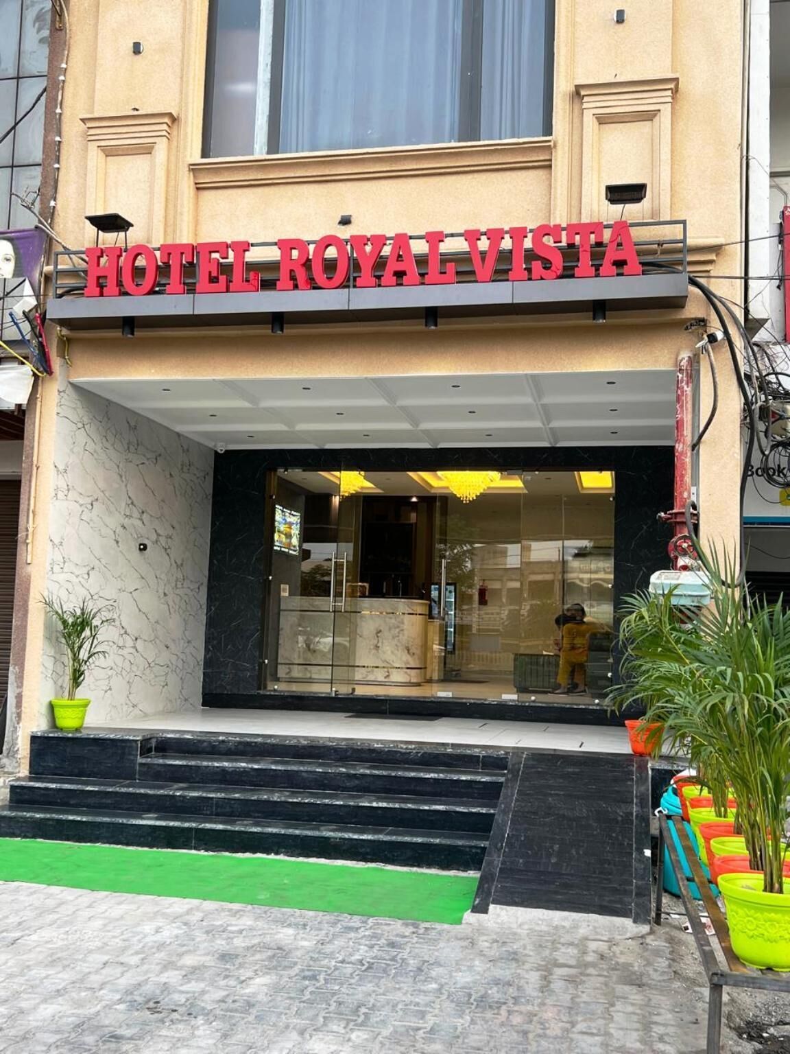The entrance of Hotel Royal Vista with a marble facade, a glass entrance, and steps leading up to the door.