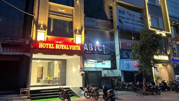 Um hotel chamado "Royal Vista", com fachada moderna, vários andares e entrada visível.
