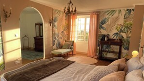 Une chambre à coucher avec un grand lit, un banc, une table et un miroir.
