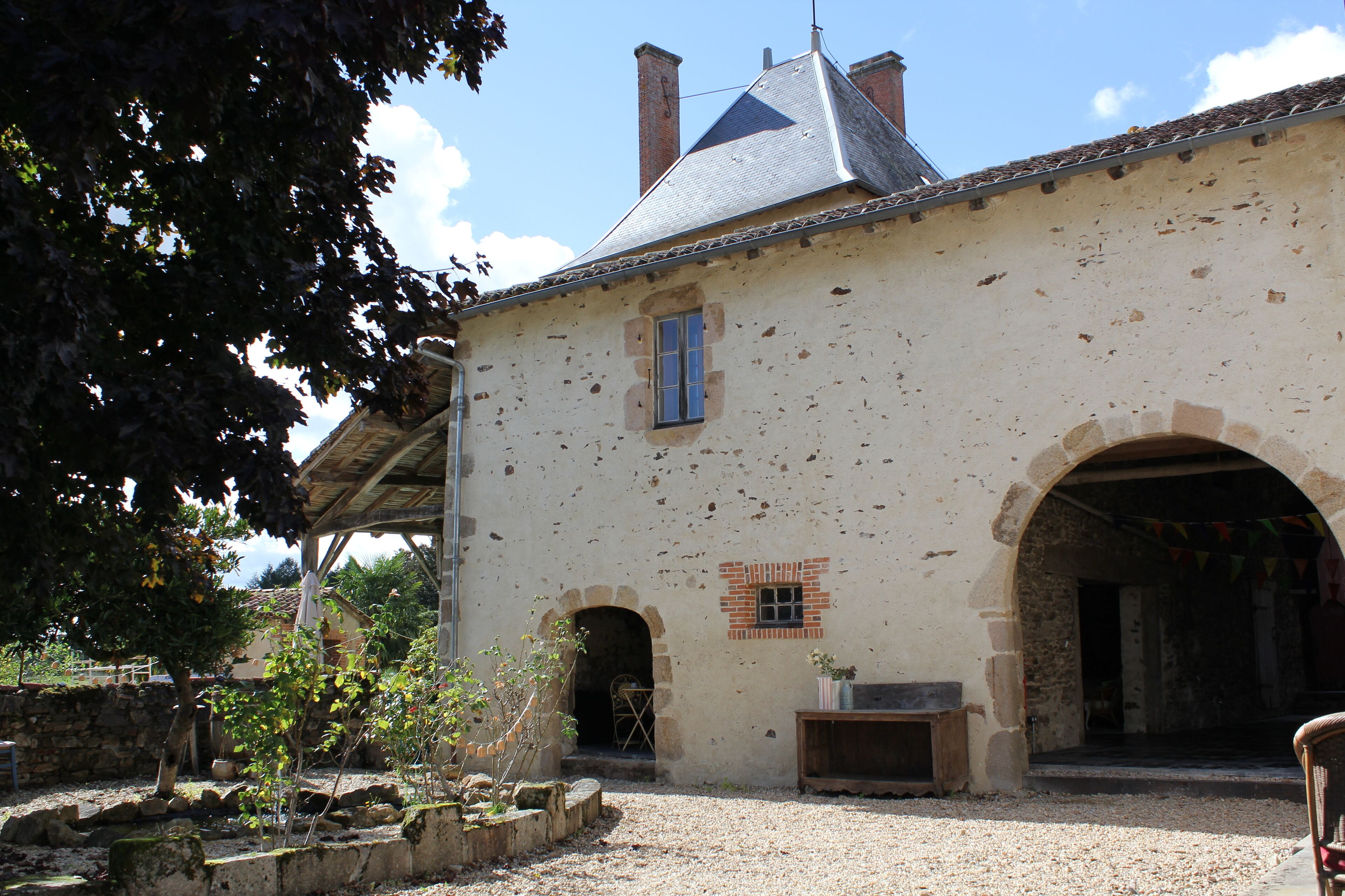 Un bâtiment de style rustique, doté d’une façade en pierre, d’un toit en tuiles et d’un petit jardin à l’avant.