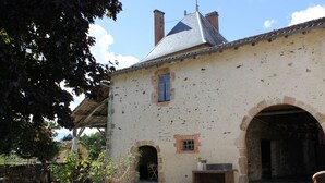Un bâtiment de style rustique, doté d’une façade en pierre, d’un toit en tuiles et d’un petit jardin à l’avant.