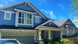 Ein zweistöckiges Haus mit Garage, überdachter Veranda und gepflegtem Rasen.