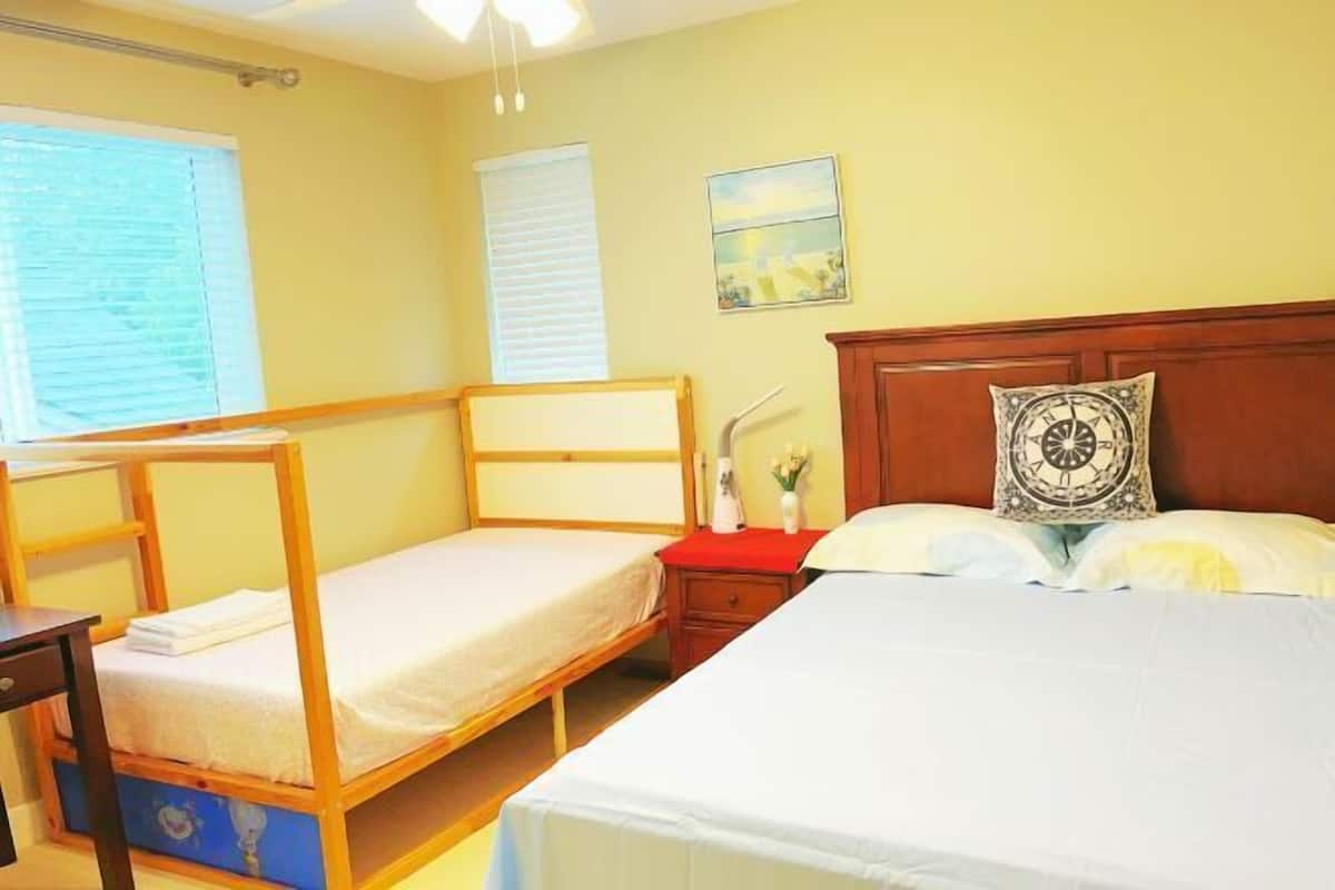 A room with two bunk beds, a wooden headboard, a bedside table with a lamp, and a wall-mounted painting.