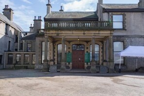 A historic building with a central entrance, flanked by two columns and a decorative balcony. - Holiday Inn LEEDS - GARFORTH by IHG (Garforth)