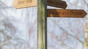 Houten bord met pijlen die wijzen naar 'Deer Hide', 'Stable Courtyard' en 'House and Chapel'.