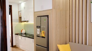 Eine moderne Küche mit weißen Schränken, einem Edelstahlkühlschrank und einer Wand in Holzoptik.