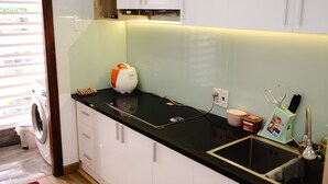 Una cocina moderna con armarios blancos, encimera negra, lavadora y un lavabo con una toalla.