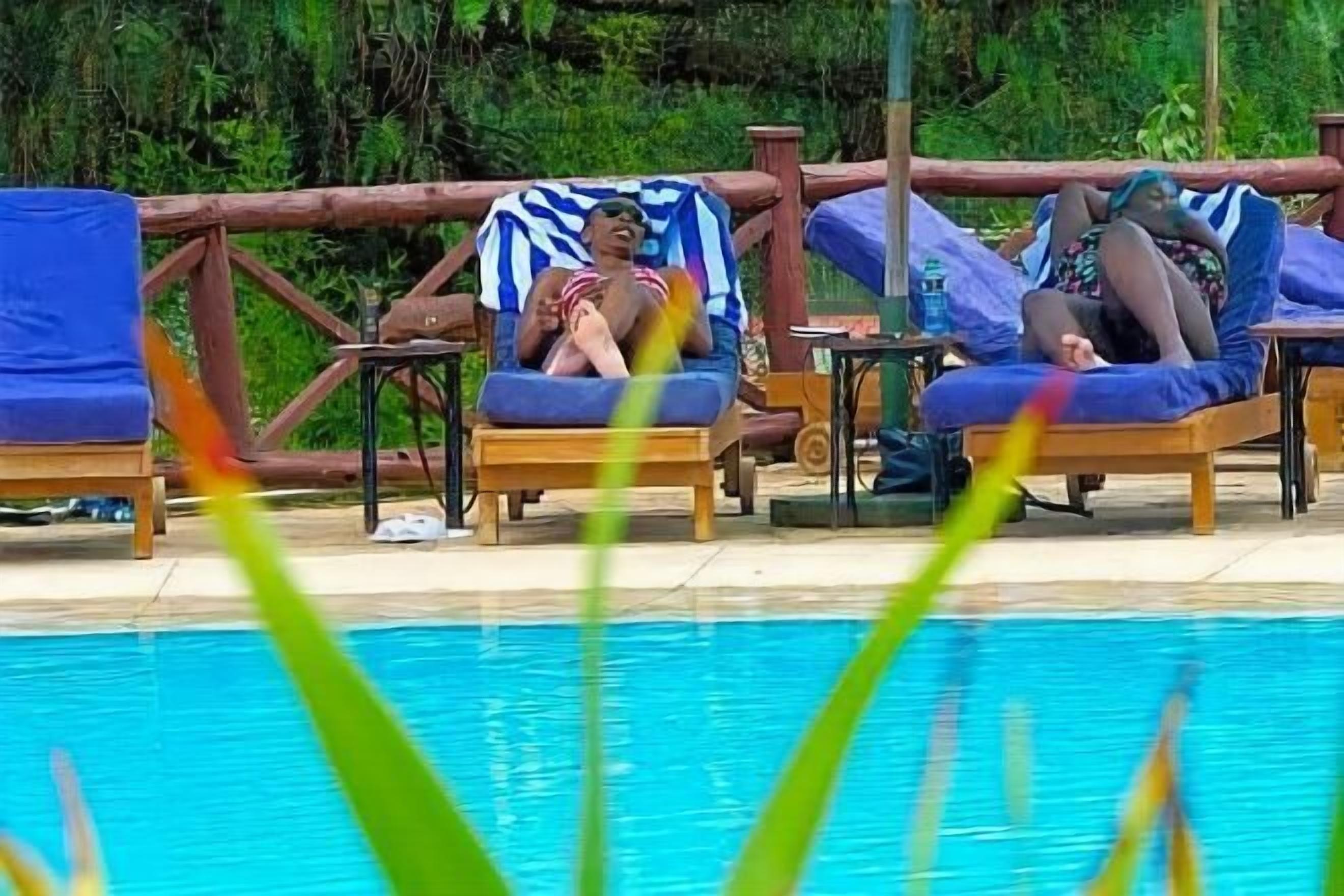Zona junto a la piscina con sillones de descanso y una terraza de madera.