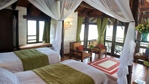 A room with two beds, a wooden ceiling, and a balcony with chairs and a table. - The Great Rift Valley Lodge & Golf Resort (Kasarani)