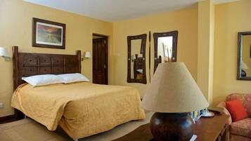 Una habitación de hotel con una cama, una mesita de noche de madera, una lámpara, un sofá y dos espejos en la pared.