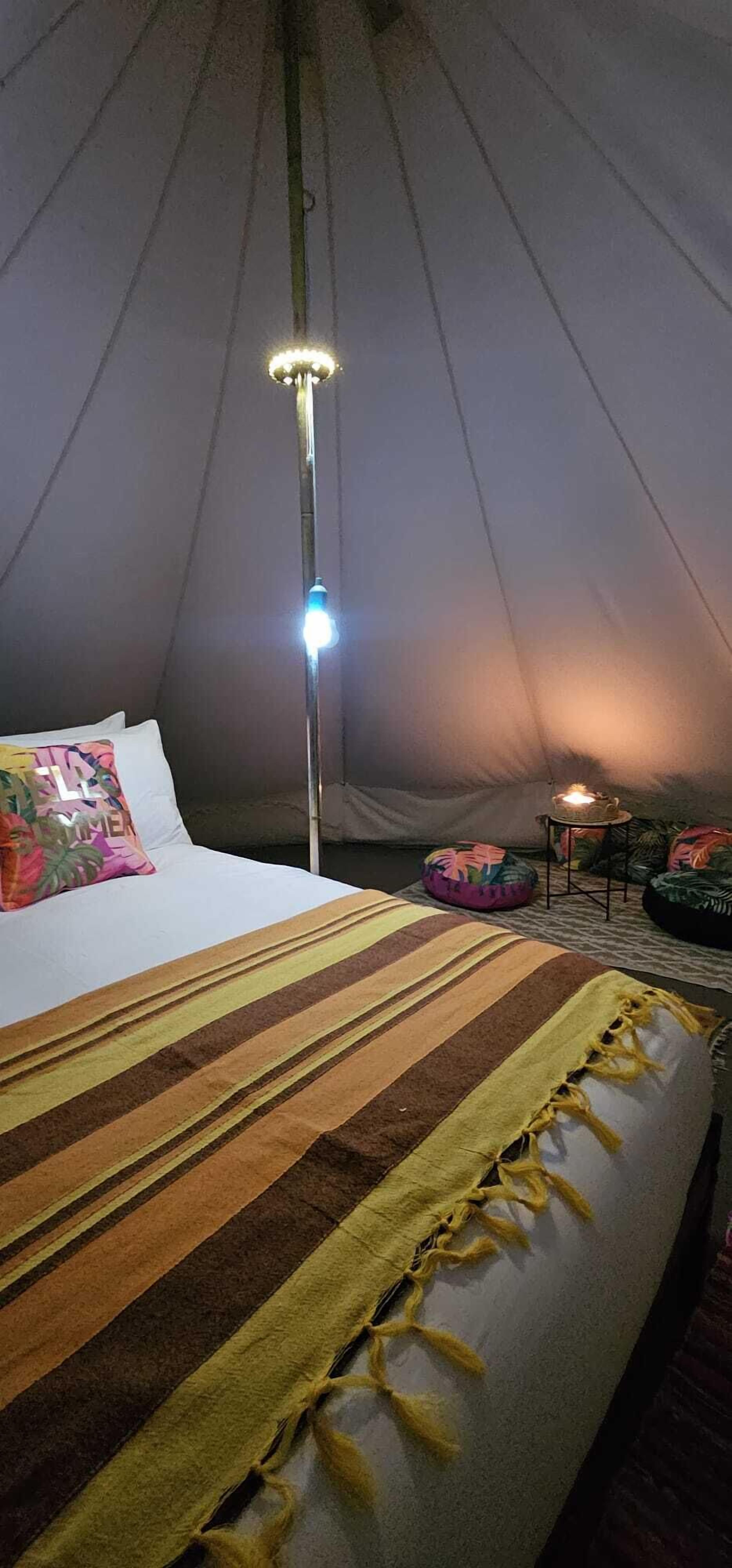 A tent with a bed, a lamp, and a small table with a candle.