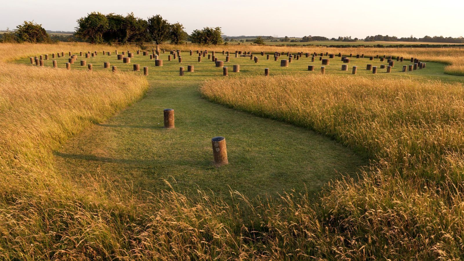 A field with hay bales and wooden posts arranged in a circular pattern.