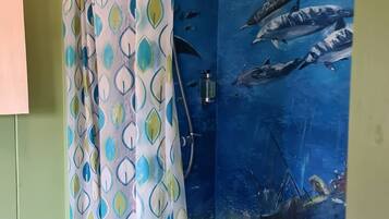 A bathroom with a shower curtain featuring a leaf pattern and an aquarium wall depicting marine life.