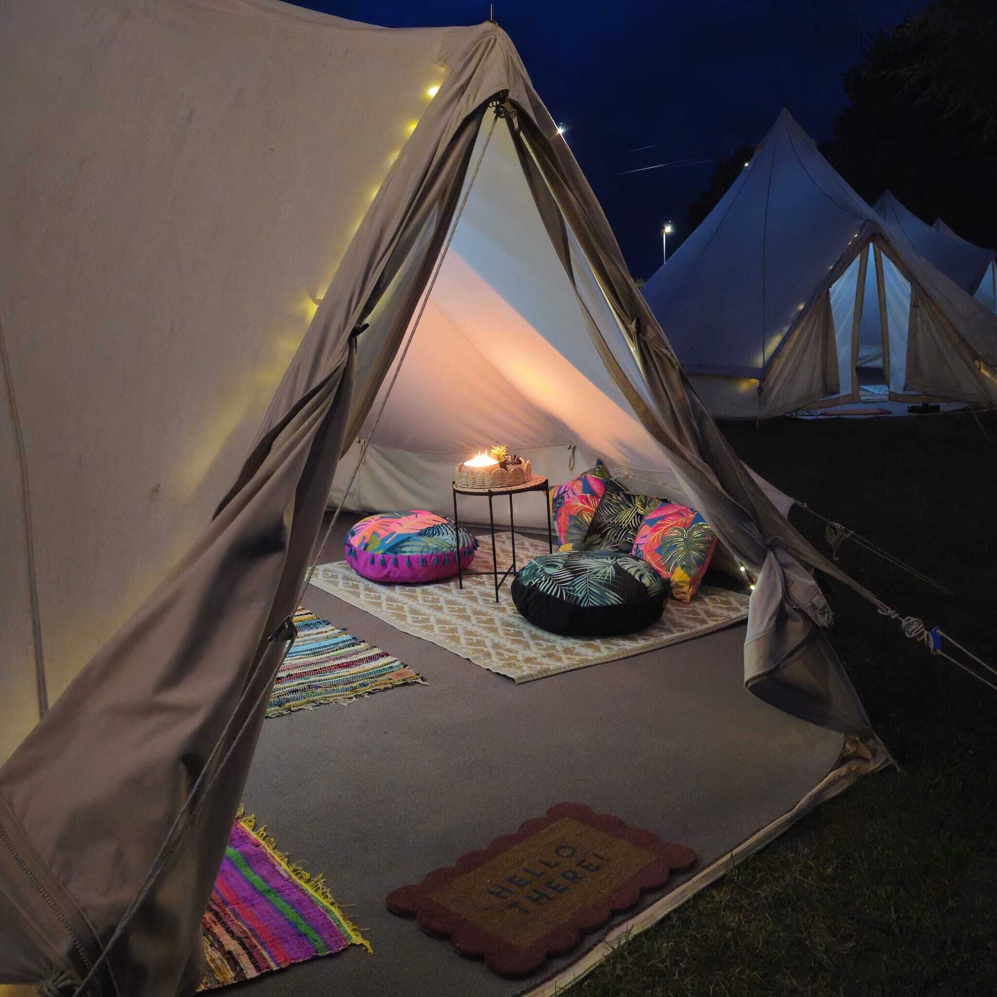 A tent with a small table and colorful cushions inside.