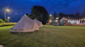 Camp de gespa amb tendes i un edifici amb llums.