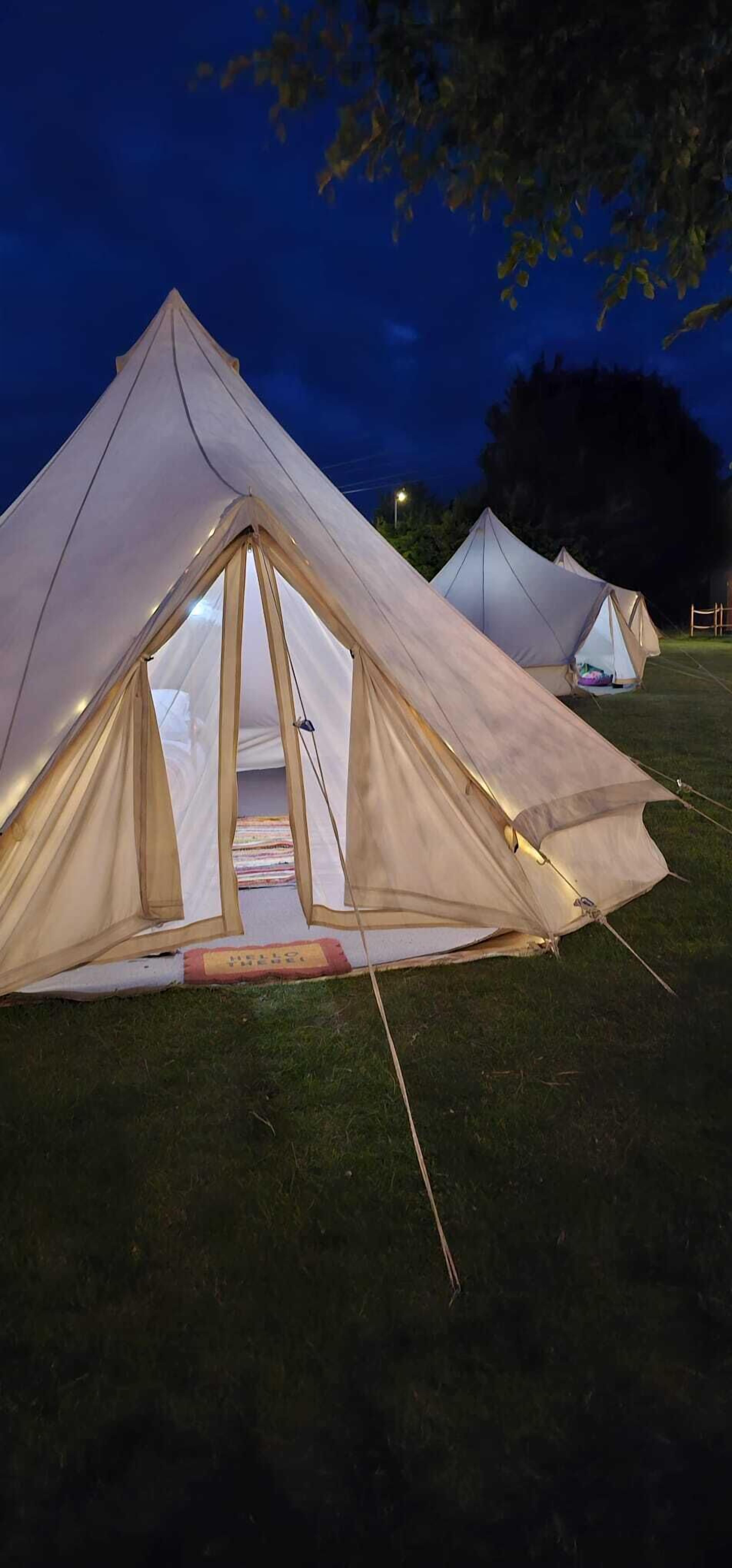 A series of large, light-colored tents set up on a grassy field at night.