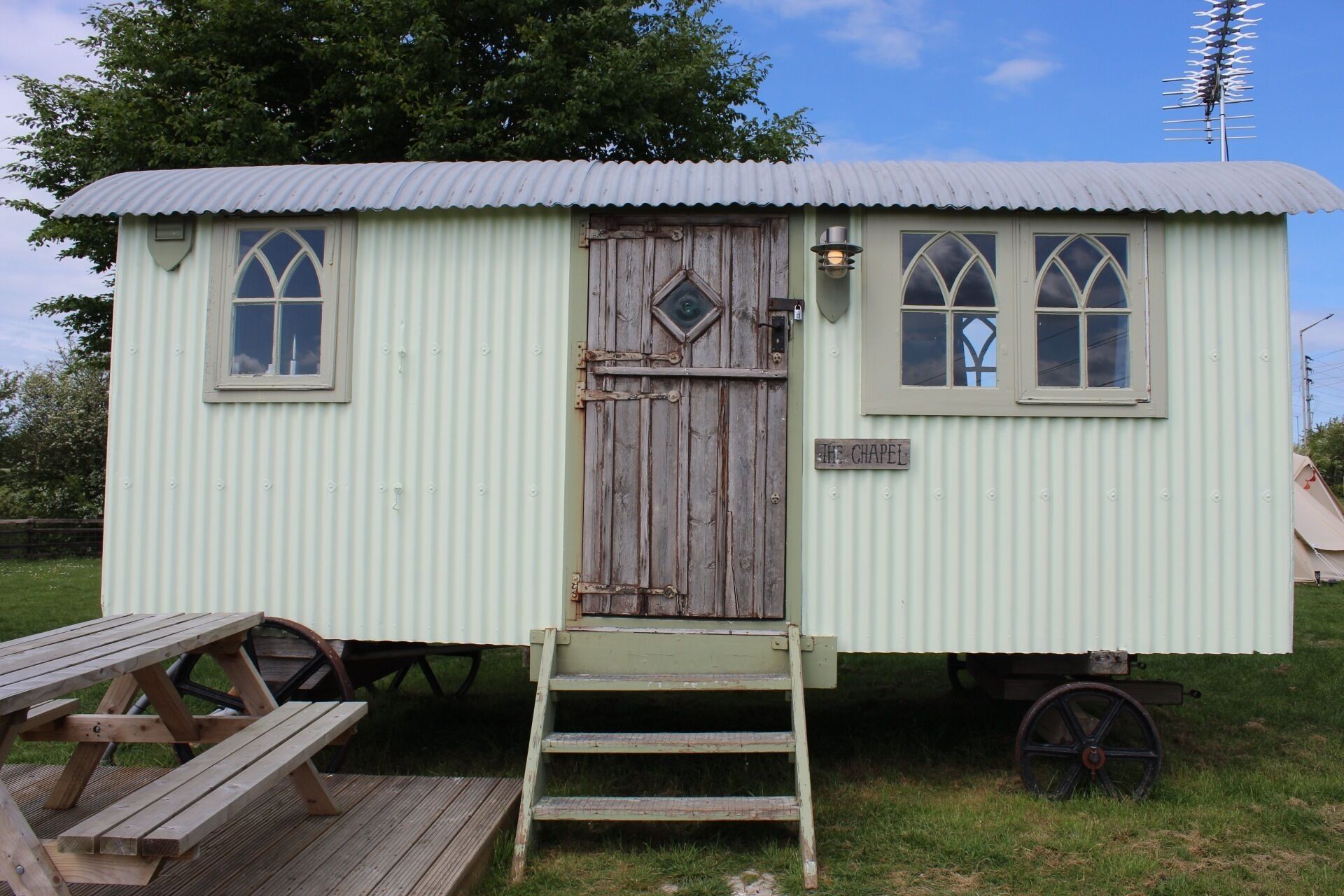 A small, single-story structure with a corrugated metal roof, a wooden door, and two windows with pointed arches.
