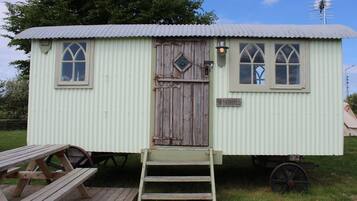 A small, single-story structure with a corrugated metal roof, a wooden door, and two windows with pointed arches.