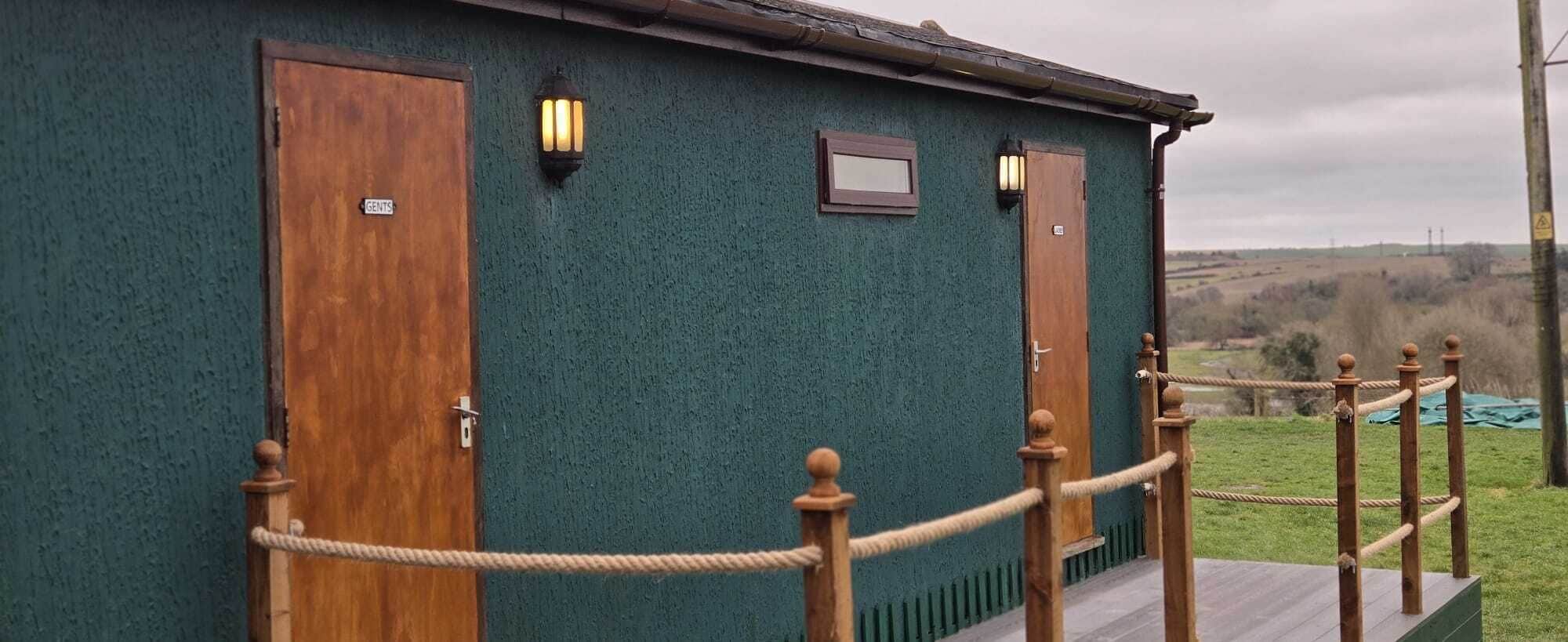 A building with two wooden doors labeled "GENTLES" and a small window.
