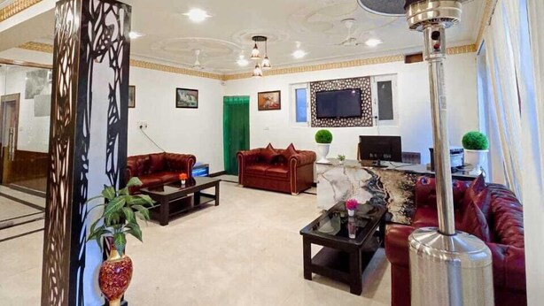 Uma sala de estar ampla, com teto alto, uma grande TV de tela plana na parede e um pilar decorativo no centro.