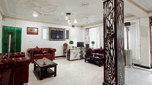 Um hall amplo com sofás de couro, balcão de recepção e padrões decorativos no teto.