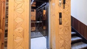 Paredes de madeira com padrões geométricos, uma porta que dá para um quarto e uma escadaria.