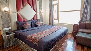 Um quarto moderno com uma cama grande, um ventilador de teto, mesa de cabeceira, sofá e janela com cortinas.