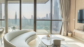 Ein modernes Wohnzimmer mit einer gebogenen Couch, einem Glastisch und Blick auf eine Stadtlandschaft durch große Fenster.