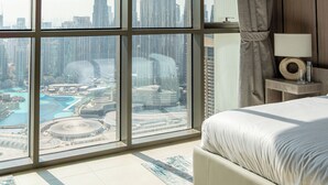 Ein Schlafzimmer mit großem Fenster und Blick auf die Stadt, ein Bett, ein Nachttisch und eine moderne Deckenleuchte.