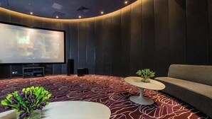 Une salle de cinéma moderne avec un mur incurvé, un grand écran et un canapé confortable.