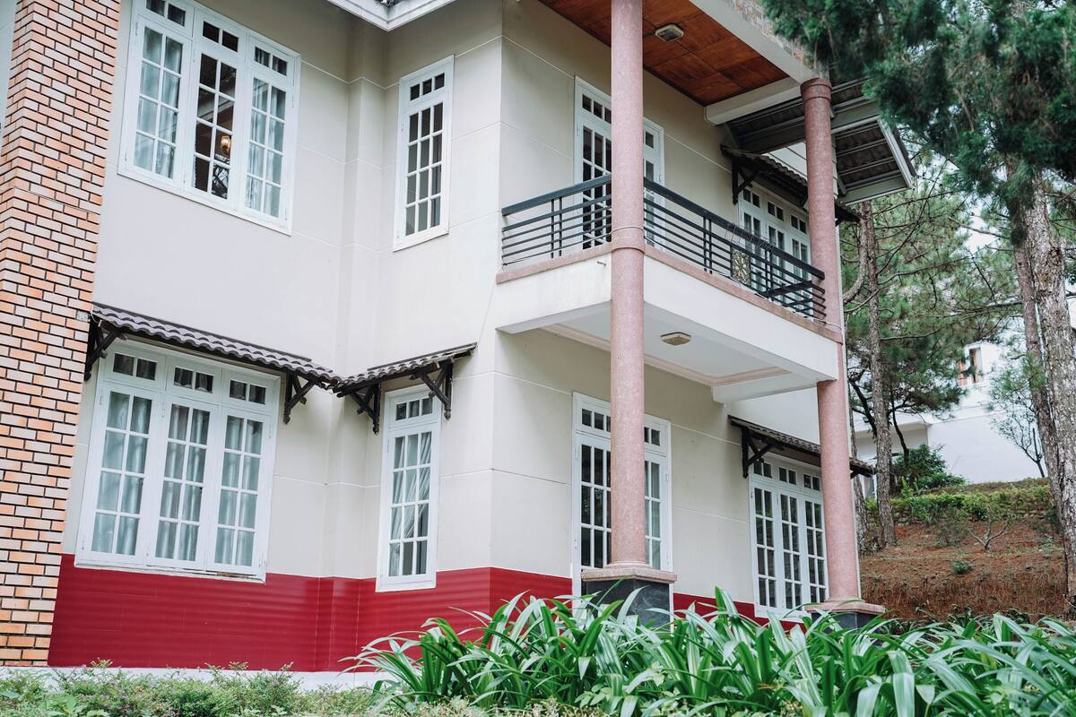 Un immeuble à plusieurs étages, doté d’une façade rouge et blanche, de nombreuses fenêtres et d’un balcon.
