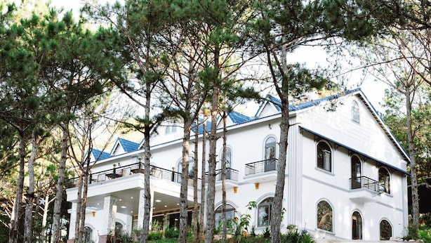 Un edificio grande y blanco con varios balcones, rodeado de árboles.