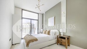Een moderne slaapkamer met een groot bed, een nachtkastje en uitzicht op de stad door een groot raam.