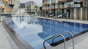 Een modern hotel met een zwembad, eigentijdse architectuur en een helder uitzicht op de omliggende gebouwen.