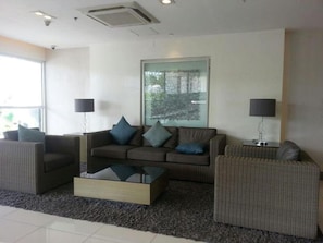 A modern living room with a sofa set, two side tables with lamps, a coffee table, and a large window with a view of trees. - Jericho's Place at Sea Residences (Pasay)