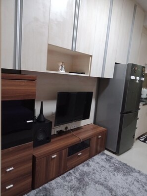 A modern kitchen with a built-in TV, a refrigerator, and wooden cabinetry. - Jericho's Place at Sea Residences (Pasay)