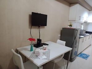 A small kitchenette with a refrigerator, microwave, and a TV mounted on the wall.